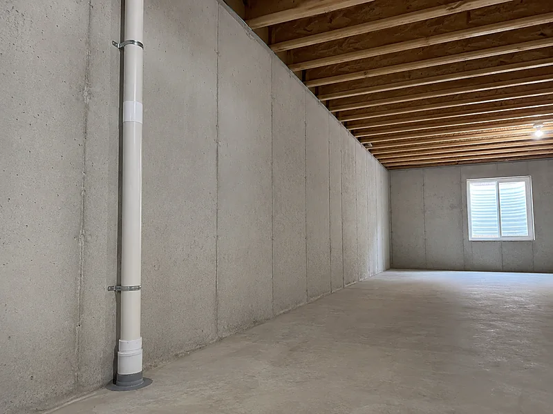 A capped passive radon vent stack with no fan, rising from a sealed basement floor penetration