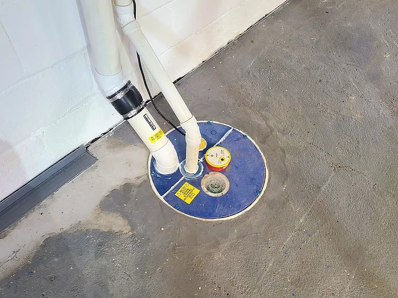 A sealed sump pit lid with a radon vent pipe drawing suction from the pit